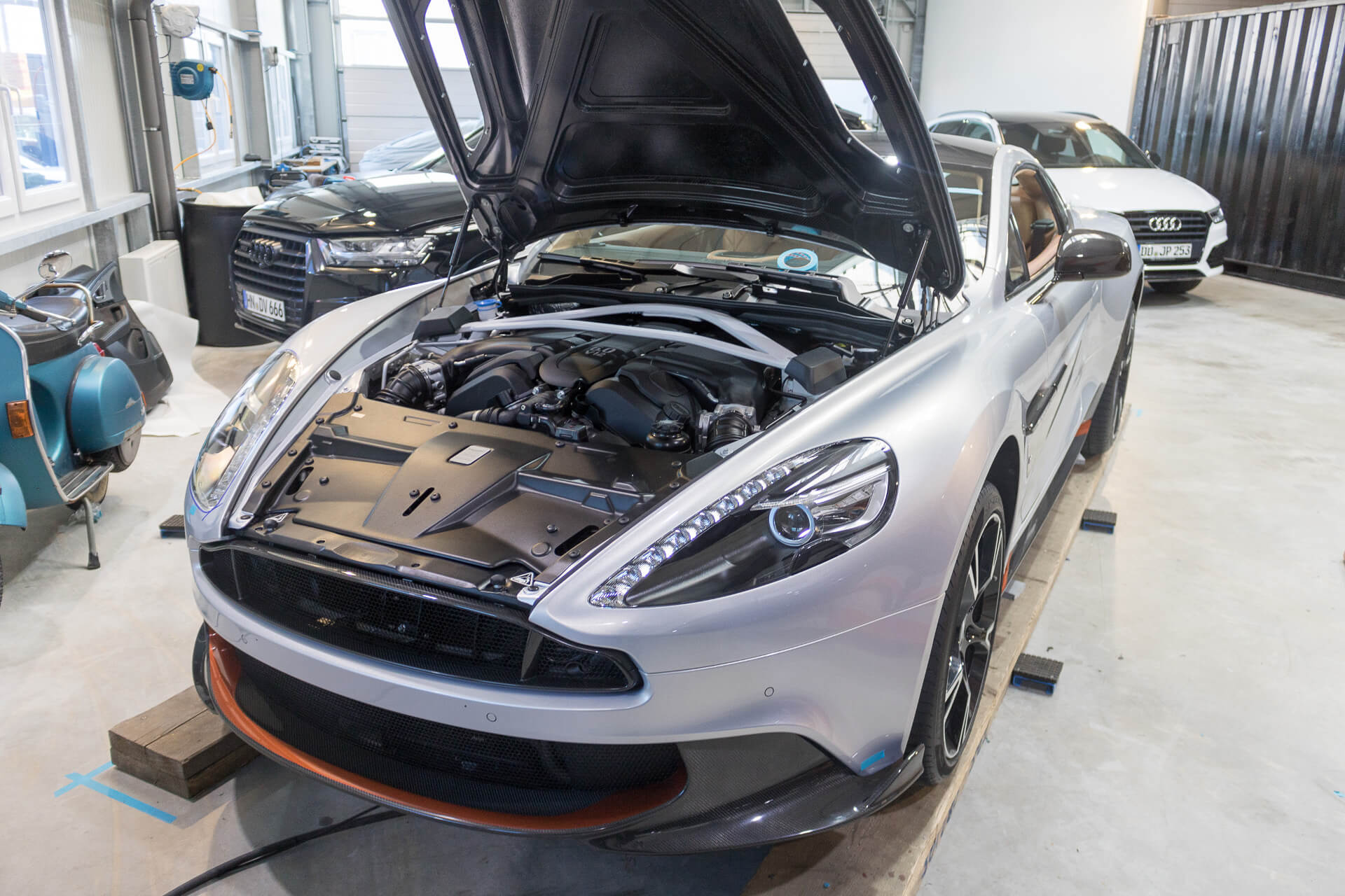 Ein silbernes Sportwagenmodell mit geöffneter Motorhaube steht in einer Werkstatt.